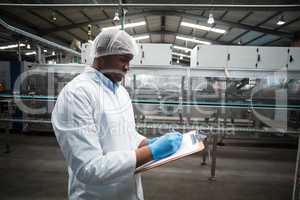 Factory engineer maintaining record on clipboard in factory