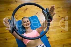 Smiling fit woman exercising with pilates ring on mat