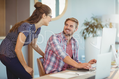 Graphic designers interacting while working on personal computer