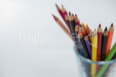 Colored pencils kept in glass on white background