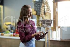 Female staff using digital tablet at counter