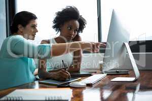 Female graphic designer pointing to desktop pc