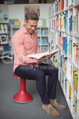 Attentive school teacher holding book in library