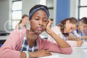 Thoughtful schoolgirl sitting in classroom