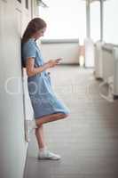 Schoolgirl using mobile phone in corridor