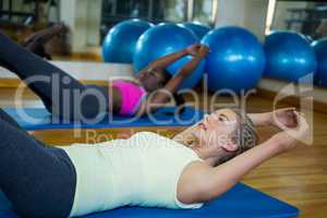 Two fit women doing stretching exercise on mat