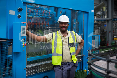 Smiling factory worker standing near machine control cabinet