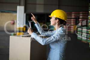 Female factory worker maintaining record on mobile phone in factory
