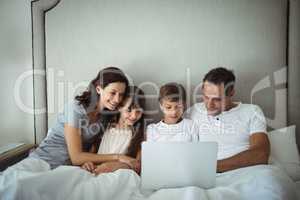 Parents and kids using laptop in bed