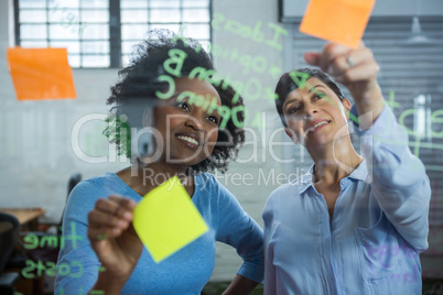 Female graphic designer pointing to the sticky notes on the glass