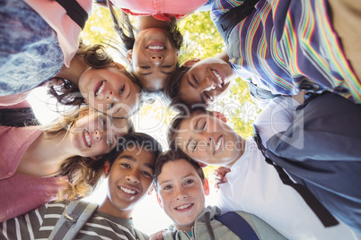 Portrait of smiling school kids forming a huddle in campus