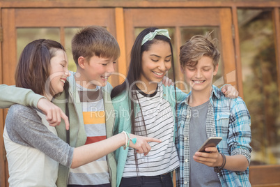 Group of smiling school friends using mobile phone