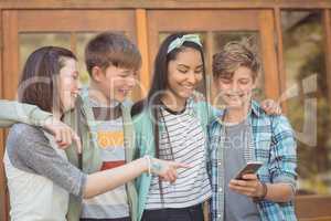 Group of smiling school friends using mobile phone
