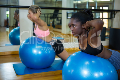 Two fit women performing pilate on exercise ball