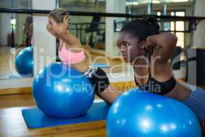Two fit women performing pilate on exercise ball