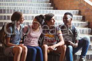 Happy classmates sitting on staircase