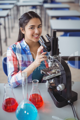 Portrait of schoolgirl experimenting on microscope in laboratory