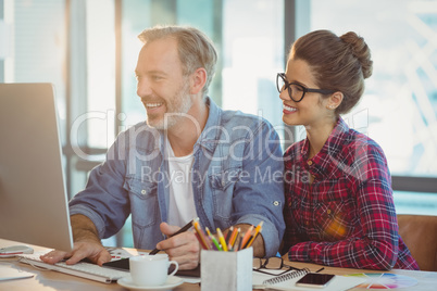 Male graphic designer working with coworker in office