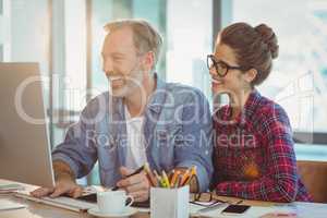 Male graphic designer working with coworker in office