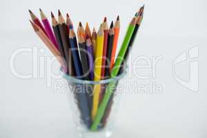 Colored pencils kept in glass on white background