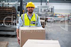 Portrait of factory worker carrying cardboard boxes