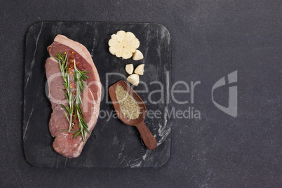 Sirloin chop, garlic and spices on black slate plate