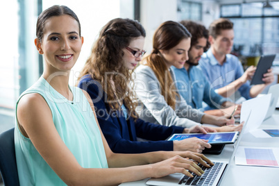 Smiling business team working on laptop and digital tablet in meeting Smiling business team working on laptop and digital tablet in meeting