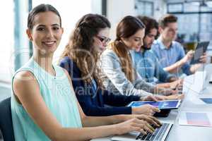 Smiling business team working on laptop and digital tablet in meeting