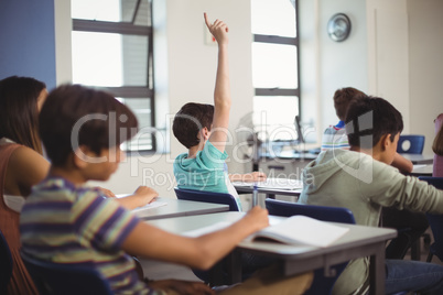 School kids raising hand in classroom