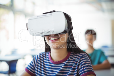 Schoolgirl using virtual reality headset in classroom