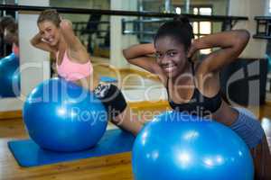 Portrait of two smiling women performing pilate on exercise ball