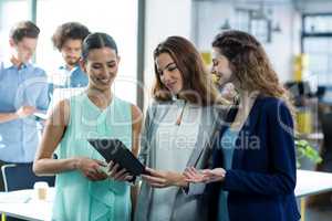 Smiling business executives using digital tablet at meeting