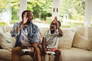Father and son giving high five to each other while playing video game