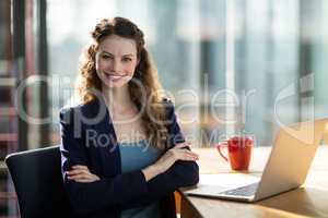 Portrait of female business executive sitting in office with laptop on table