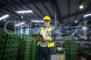 Male factory worker maintaining record on clipboard