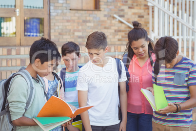 School kids discussing over text book in campus