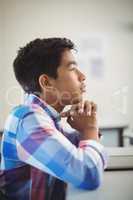 Thoughtful schoolboy sitting in classroom