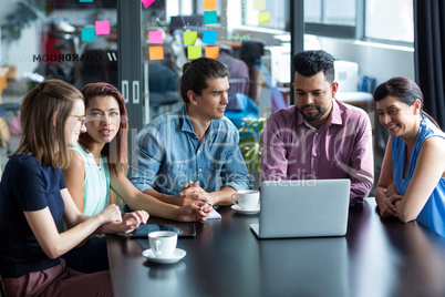 Businesspeople having discussion over laptop in office