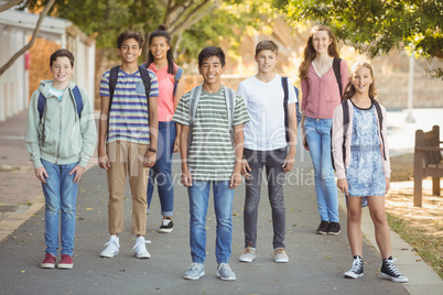 Portrait of happy students standing with schoolbag on road