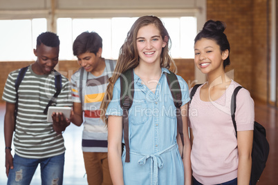 Portrait of schoolgirls standing with classmate with classmates in background