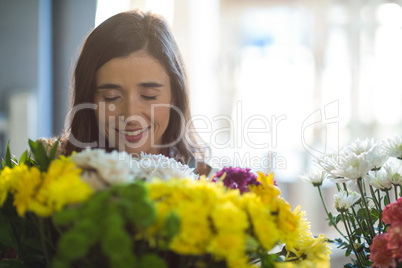 Smiling woman holding a bouquet with eyes closed in the florist shop