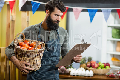 Vendor holding a clipboard and a basket of tomatoes