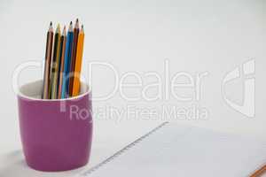 Colored pencils kept in cup and notepad