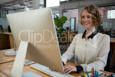Female graphic designer smiling while using desktop pc