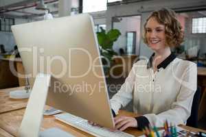 Female graphic designer smiling while using desktop pc