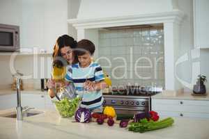 Mother and son mixing the salad in kitchen