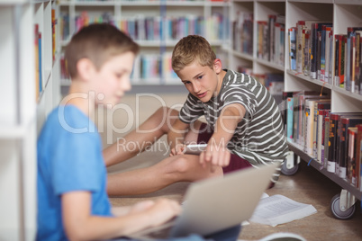 Attentive schoolboys studying in library