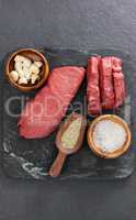 Beef steak, salt and spices on black slate plate
