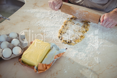 Hands sheeting the dough with rolling pin in kitchen