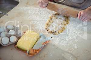 Hands sheeting the dough with rolling pin in kitchen